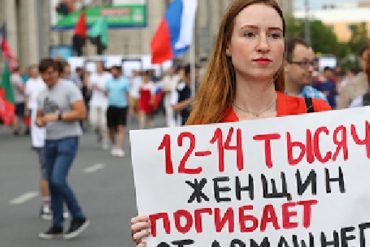 Жертвы домашнего насилия в России (молодая женщина на митинге держит плакат, на котором написано, что 12-14 тысяч женщин погибает от домашнего насилия в России ежегодно).