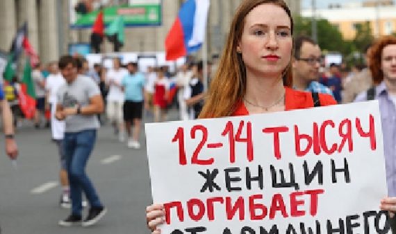 Жертвы домашнего насилия в России (молодая женщина на митинге держит плакат, на котором написано, что 12-14 тысяч женщин погибает от домашнего насилия в России ежегодно).