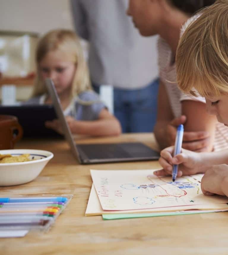 Родителей волнует, как перевести на домашнее обучение своих детей. На картинке дети занимаются за семейным столом.