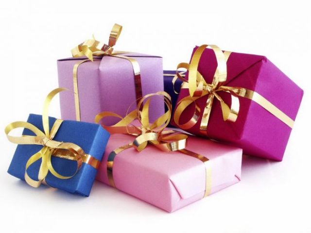 Много подарков. Коробки разной величины обернуты плотной бумагой светло-красного, ярко-розового, глубокого синего, цвета фукси, обвязаны шикарной золотой лентой.