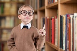 мальчик младшего школьного возраста в очках в библиотеке с осмысленным взглядом, умный, одаренный