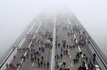 Взаимопонимание между людьми. Большой пешеходный мост, по которому идут группы людей в разных направлениях.