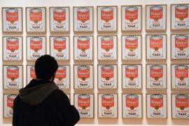 Парень с недоумением смотрит на картину, на которой изображены 32 банки супа, выстроившиеся в четыре ряда. Неужели это главные человеческие ценности в жизни?