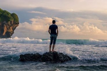 Зачем мне нужна любовь? Этот вопрос задает себе мужчина, который созерцает волны моря, стоя на камне в воде.