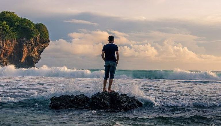 Зачем мне нужна любовь? Этот вопрос задает себе мужчина, который созерцает волны моря, стоя на камне в воде.