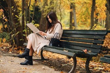 на картинке изображена сидящая в парке на скамейке девушка с интересом читающая статью в газете на актуальную тему.